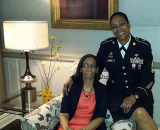 Jones posing in uniform with an arm around her mother, who is sitting in an armchair.