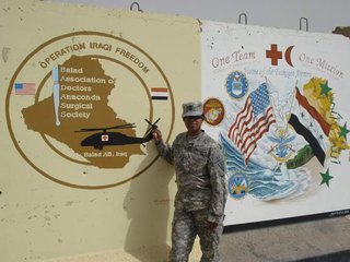 Jones in uniform at Balad Airbase, Iraq, standing in front of a wall mural that says "Operation Iraqi Freedom."