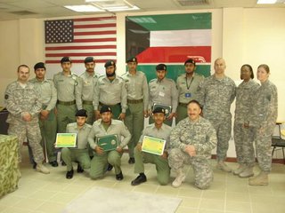 Jones and a group of service members in uniform in Kuwait, with an American flag and Kuwait flag behind them.